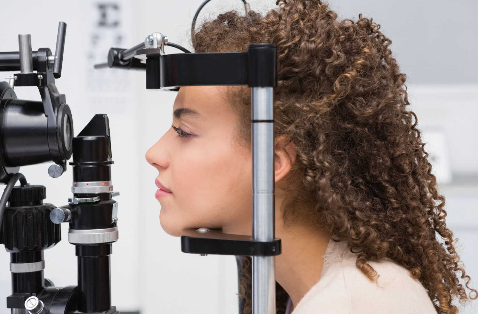 A young girl is undergoing an eye exam with the use of a sit lamp.