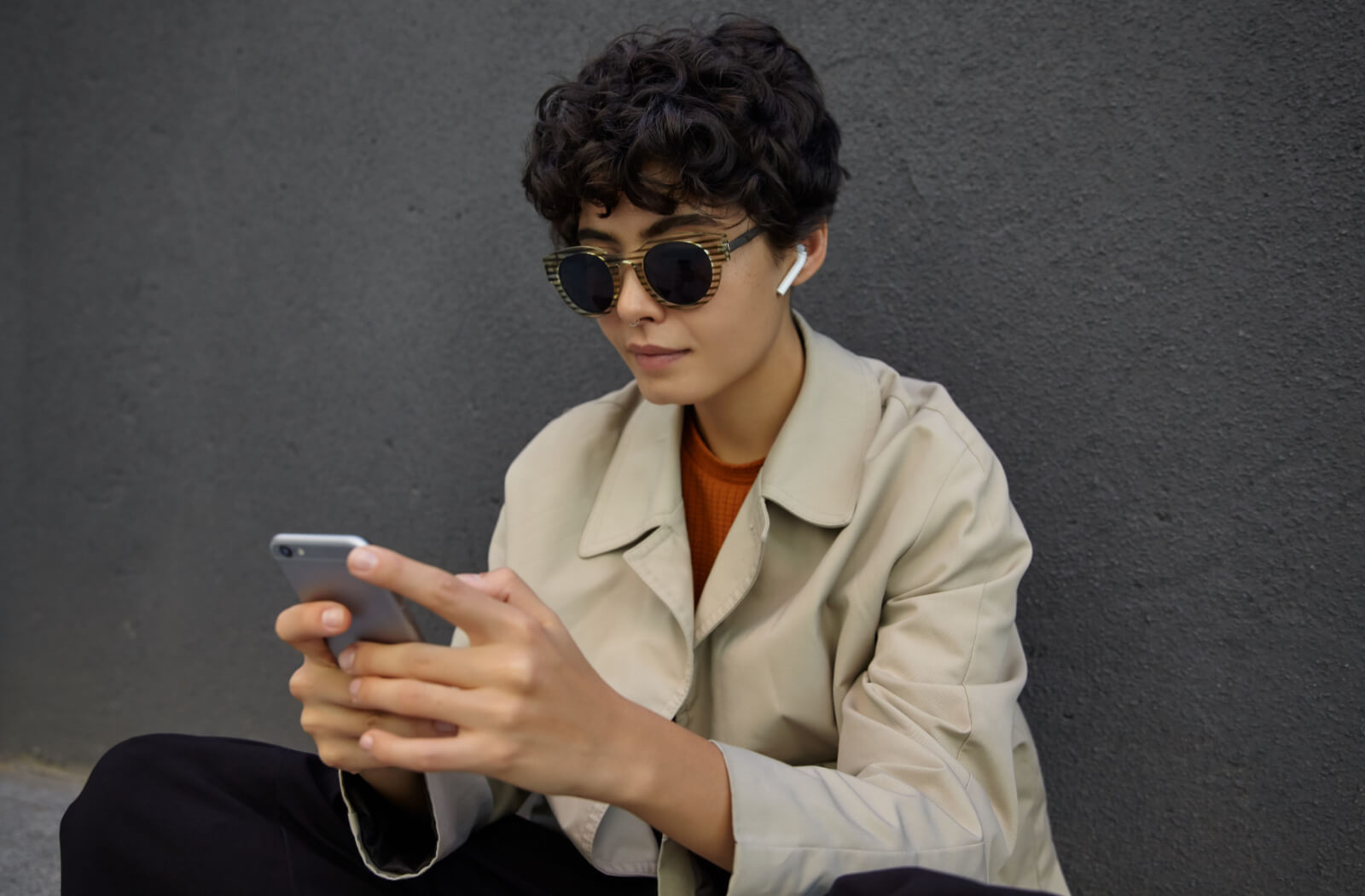 A young woman wearing a pair of stylish polarized sunglasses using her smartphone.