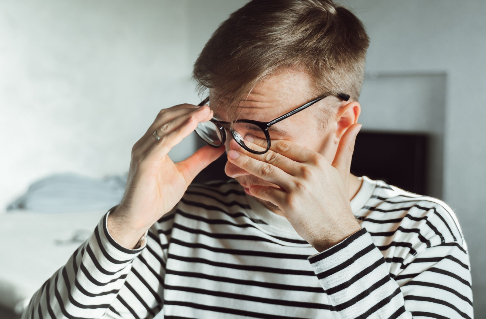 A man rubbing his eyes under his glasses trying to get rid of his blurry vision due to dry eye.