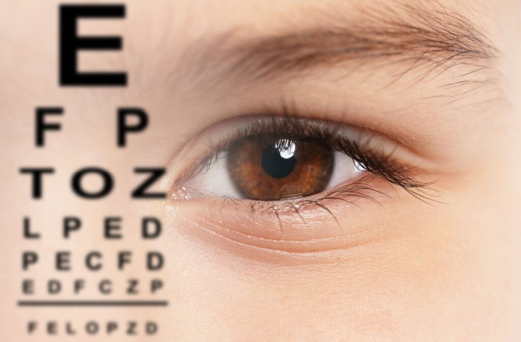 A close up of a child's eye on the right and a snellen chart on the left.