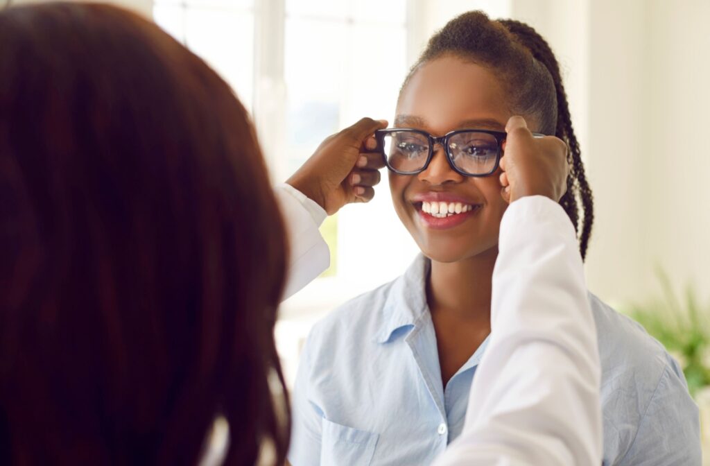 An optometrist assists a young patient with picking out prescription glasses.