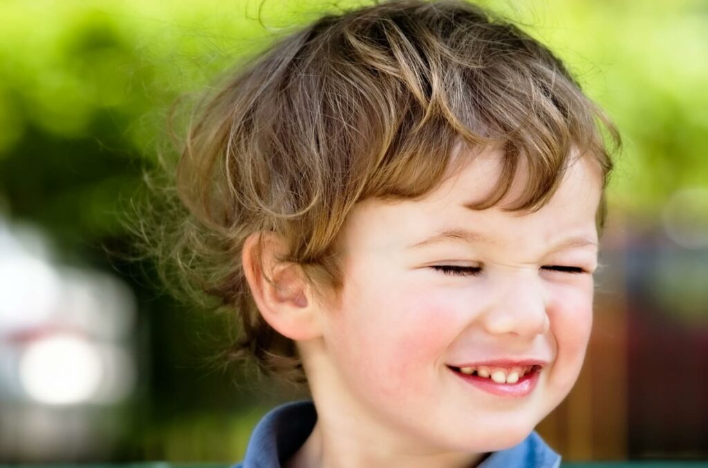 A close-up view of a child smiling and blinking.