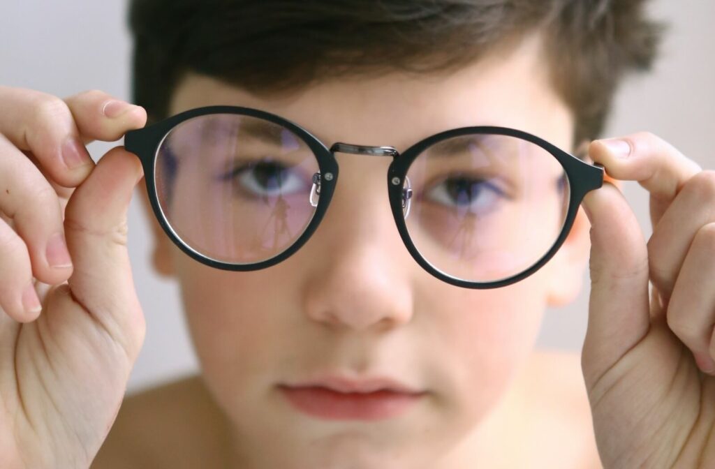 A child shows of their eyeglasses that feature specialized lenses to help slow myopia progression and correct their vision.