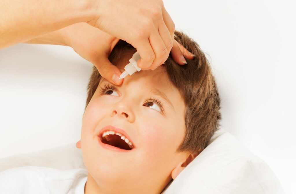 A close-up image of a parent helping their child with atropine eye drops to slow myopia progression in their child's eyes.